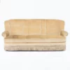Sofa Retro z Frędzlami. Stara sofa retro w beżowym kolorze, ozdobiona kremowymi frędzlami na dolnej krawędzi. Idealna do wynajmu na różne eventy we Wrocławiu. Sofa posiada wysokie oparcie podzielone na trzy segmenty, szerokie siedzisko oraz zaokrąglone podłokietniki, co dodaje komfortu. Staromodny design sprawia, że sofa doskonale nadaje się jako element scenografii czy do przytulnych stref chillout na ślub, wesele lub dowolne inne wydarzenie. Dostępna w wypożyczalni dekoracji RENT4EVENTS, ta sofa łączy w sobie wygodę i retro styl, tworząc perfekcyjne miejsce do siedzenia na każdym evencie. rent4events.pl wypożycz wrażenia - rent4wedding.pl zachowaj wspomnienia.