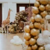 Dekoracja eventowa w stylu Safari Boho z dużą figurką żyrafy, otoczoną balonami w odcieniach złota, brązu i bieli. Tło zdobi motyw skóry żyrafy, co podkreśla egzotyczny klimat aranżacji. Na pierwszym planie widoczny jest balonowy łuk, tworzący elegancki akcent. Przy stole znajdują się plecione poduszki oraz naturalne dekoracje z suszonych roślin, wprowadzające przytulność w stylu boho. Idealna dekoracja na ślub, wesele lub event we Wrocławiu i okolicach, oferowana przez wypożyczalnię rent4events.pl - rent4events.pl wypożycz wrażenia, rent4weddings.pl zachowaj wspomnienia.