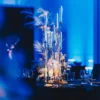 Elegancka kompozycja dekoracji stołu, z wysokim Złotym Kandelabrem Glamour, białymi kwiatami i złotymi akcentami, idealna na śluby i eventy. Całość to częś dekoracji w stylu Winter Party. Chłodne, niebieskie oświetlenie wspaniale kontrastuje z ciepłymi tonami dekoracji, tworząc wyrafinowaną scenografię. Wypożyczalnia dekoracji Rent4Events i Rent4Weddings oferuje perfekcyjne scenografie na eventy we Wrocławiu, od ślubów po imprezy okolicznościowe - rent4events.pl wypożycz wrażenia, rent4weddings.pl zachowaj wspomnienia. Fot. Daniel Mofina @daniel.mofina @mofina.art.