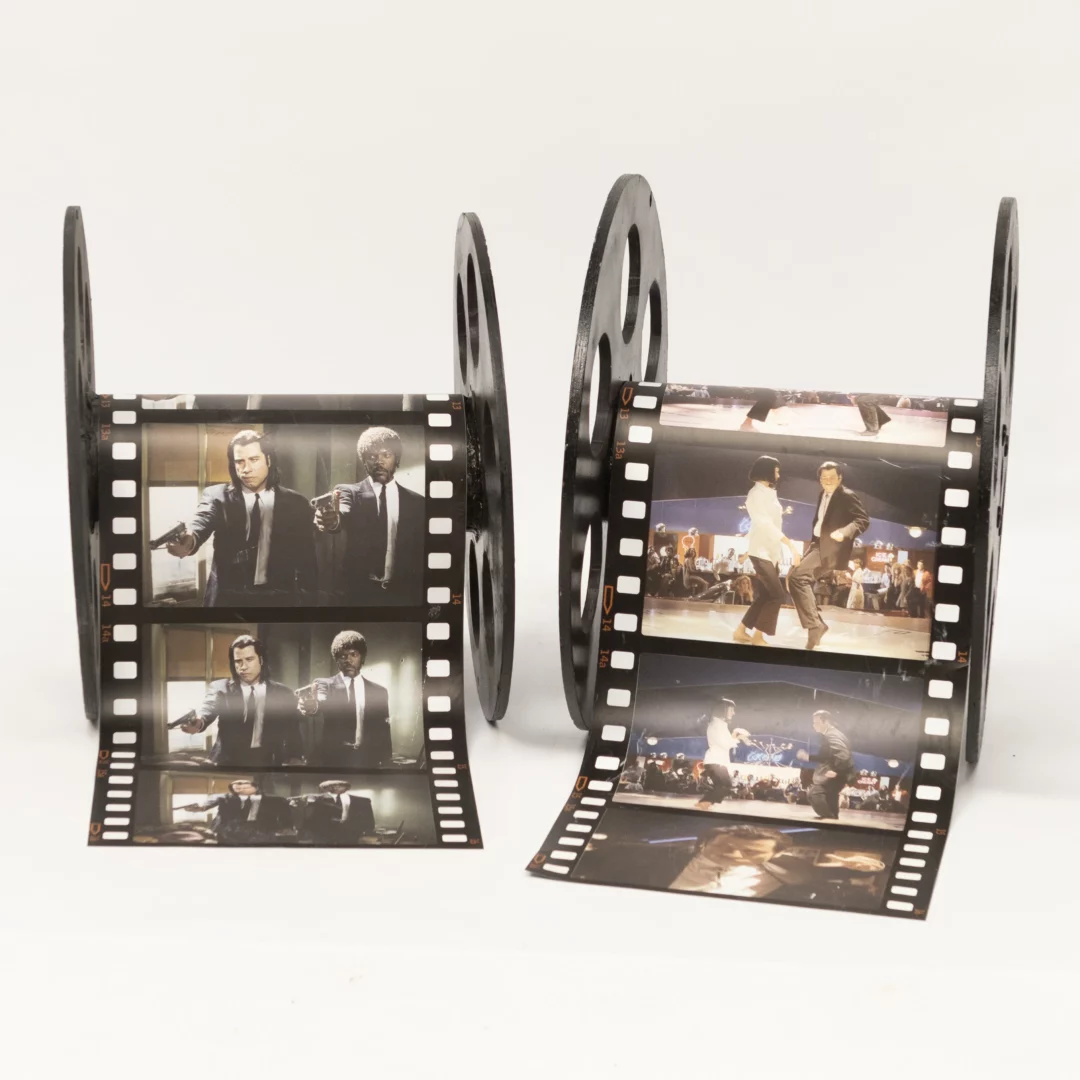 Szpule Filmowe XXL, Pulp Fiction. Dwie czarne szpule filmowe z rozwiniętymi taśmami, przedstawiające kultowe kadry filmowe – sceny akcji i tańca - z filmu Pulo Fiction. Idealna dekoracja na filmowe event we Wrocławiu. Elementy te oferowane są przez wypożyczalnię RENT4EVENTS pod markami rent4events.pl oraz rent4weddings.pl. Doskonale pasują jako elementy Oscarowej scenografia, łącząc filmowy klimat z elegancją. rent4events.pl wypożycz wrażenia, rent4wedding.pl zachowaj wspomnienia.
