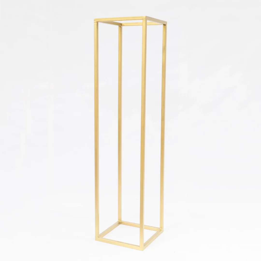 Złoty Słupek 206 cm. Złoty, szeroki słupek dekoracyjny o wysokości 206 cm i podstawie 50x50 cm, wykonany z kwadratowego profilu stalowego. Idealny na kompozycje kwiatowe i inne dekoracje podczas ślubów, wesel i eventów. Geometryczna, minimalistyczna forma doskonale pasuje do stylu glamour i romantycznego, podkreślając elegancję i prestiż aranżacji. Dostępny w wypożyczalni dekoracji we Wrocławiu – rent4events.pl oraz rent4weddings.pl - rent4events.pl wypożycz wrażenia, rent4weddings.pl zachowaj wspomnienia.