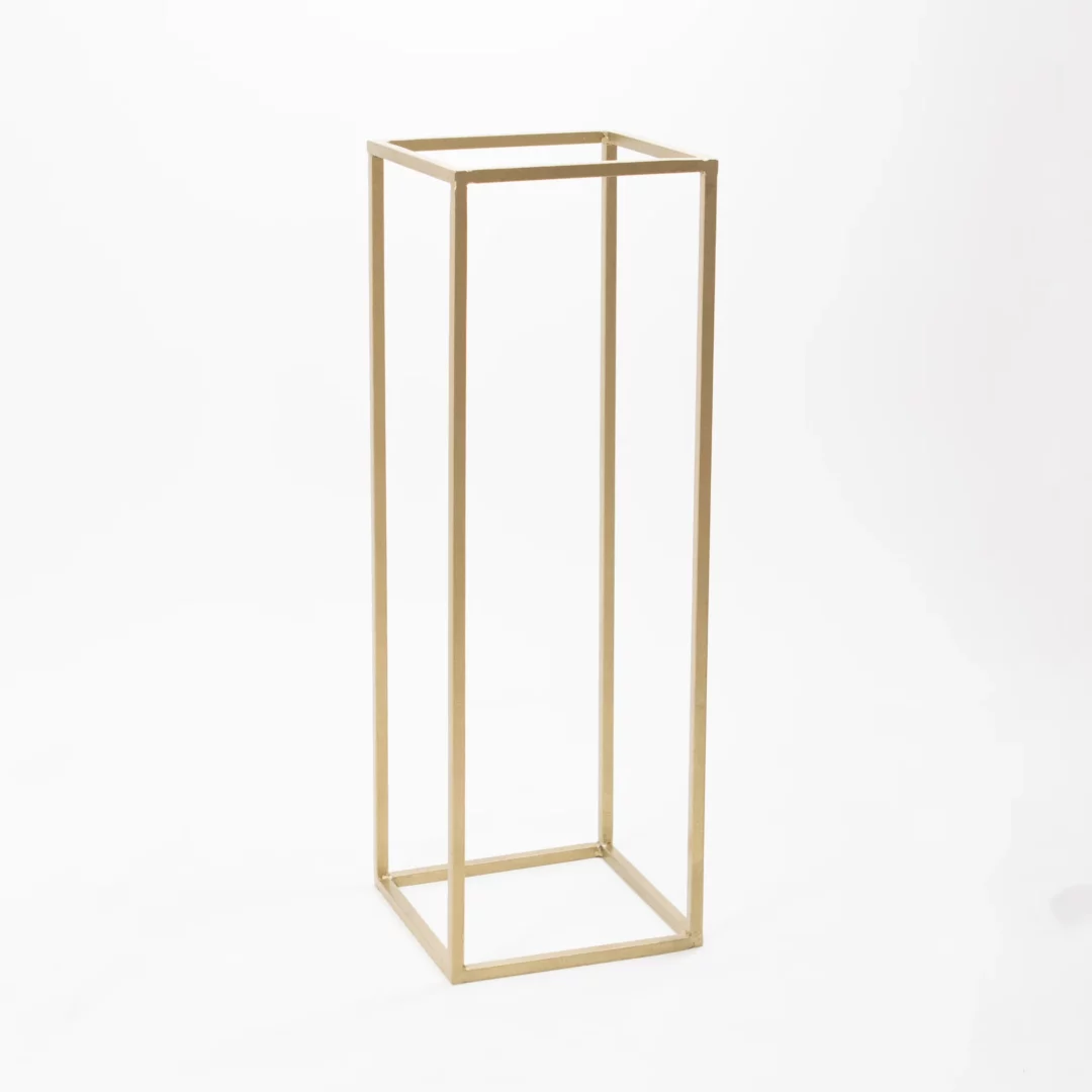Złoty Stojak Na Kwiaty 60 cm o podstawie 20x20 cm, idealny do kompozycji kwiatowych na stoły podczas ślubów, wesel i eventów. Geometryczny, minimalistyczny design doskonale pasuje do stylu glamour, podkreślając prestiż i elegancję wydarzenia. Złoty kolor współgra z dowolnymi aranżacjami, a podkładka jest uwzględniona w wynajmie. Dostępny w wypożyczalni dekoracji we Wrocławiu – rent4events.pl oraz rent4weddings.pl - rent4events.pl wypożycz wrażenia, rent4weddings.pl zachowaj wspomnienia.