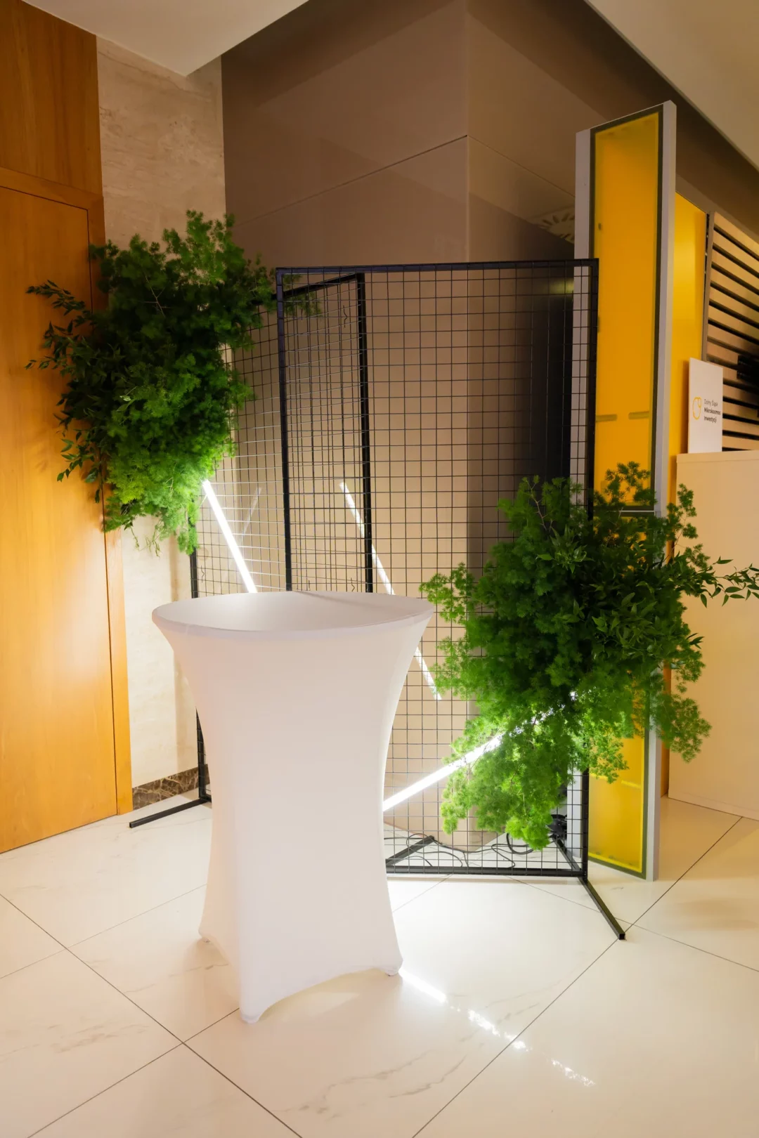 Elegancka aranżacja eventowa z wykorzystaniem czarnej ścianki kratkowej, stolika koktajlowego w białym, elastycznym pokrowcu oraz dekoracji z żywej zieleni to nowoczesna scenografia dostępna w wypożyczalni Rent4Events / Rent4wedding Wrocław. Połączenie klasycznej formy z industrialną kratką i oświetleniem LED tworzy efektowną strefę powitalną. Tło z kratki idealnie sprawdzi się jako baza do zawieszania florystyki i świetlnych akcentów. Całość można wypożyczyć na stronie rent4events.pl oraz rent4weddings.pl - rent4events.pl wypożycz wrażenia, rent4wedding.pl zachowaj wspomnienia. Fot. @karolinakiec_fotografia.